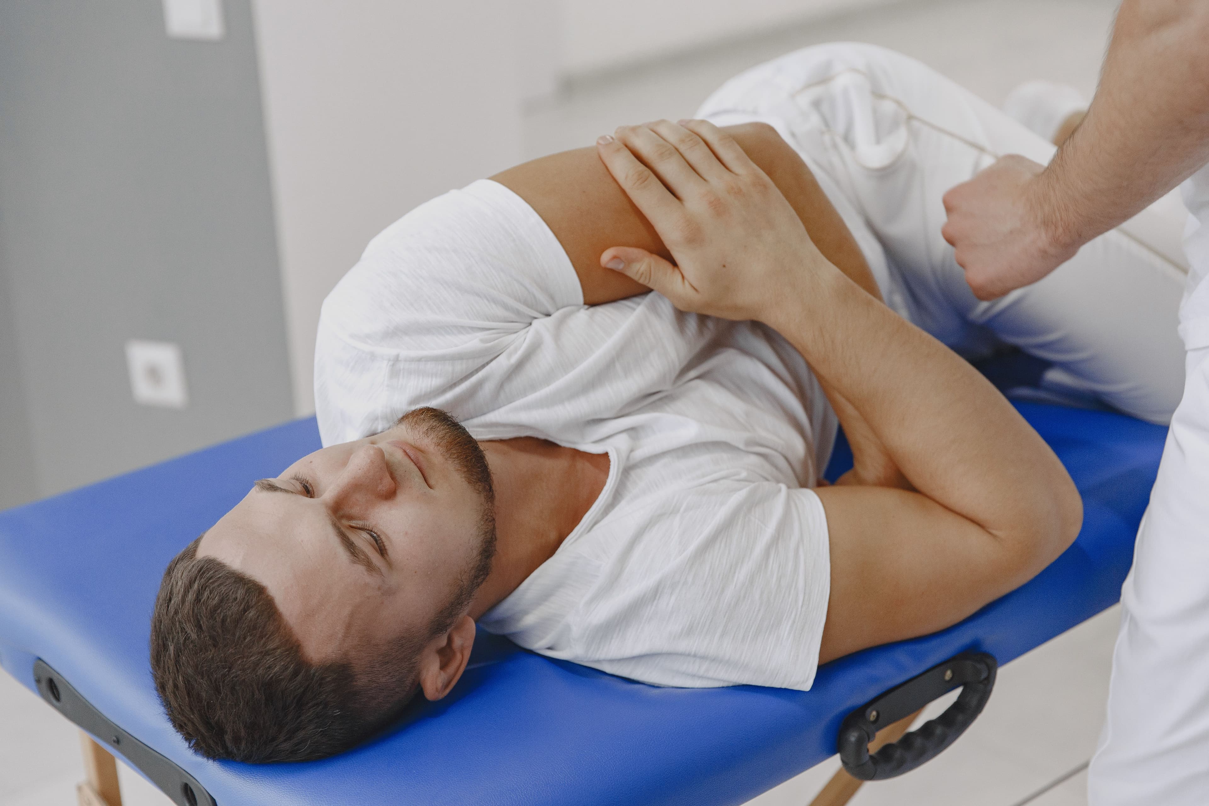 Physiotherapist guiding a patient through a supported stretch on a treatment table