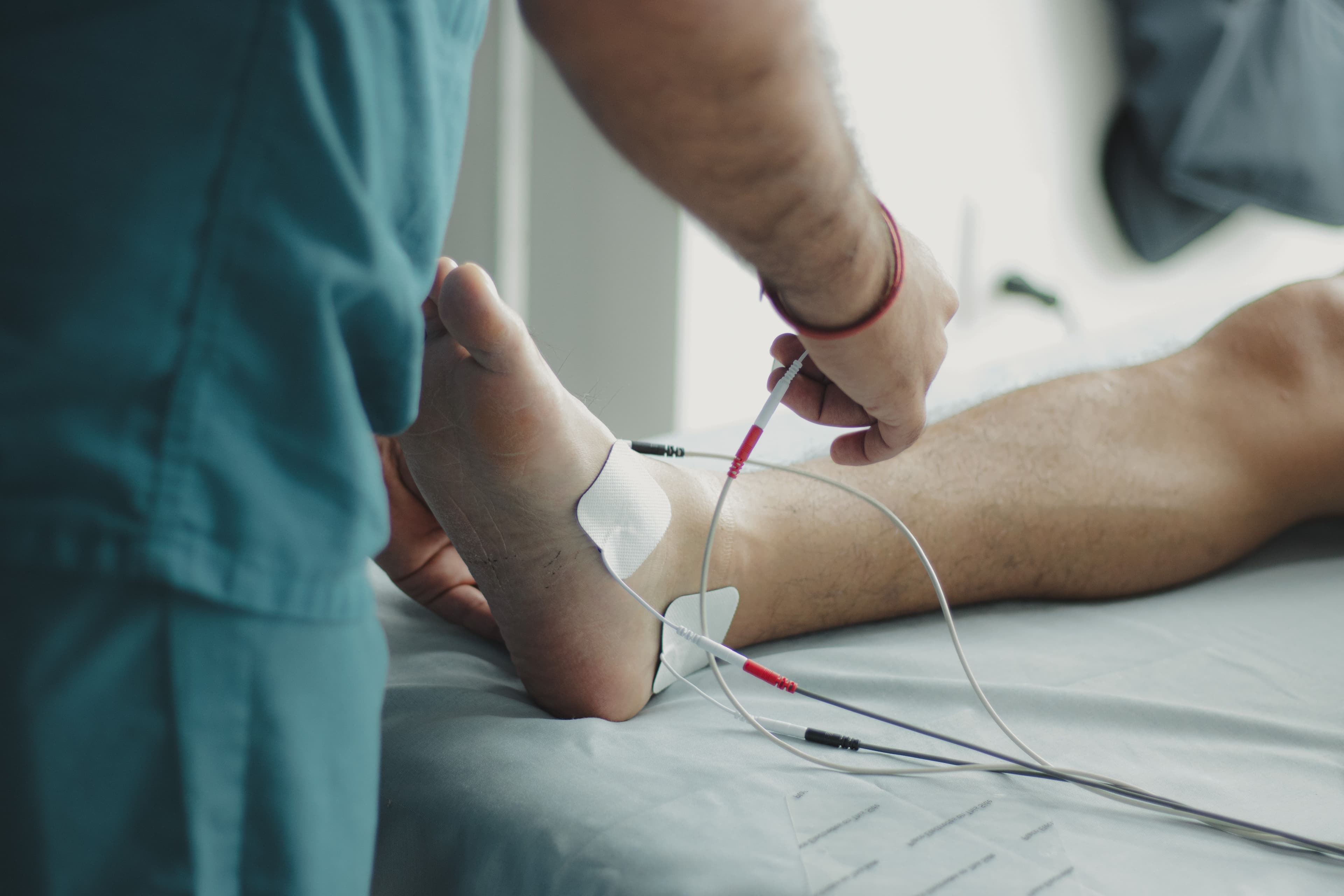 Clinician attaching electrotherapy pads to a patient's ankle